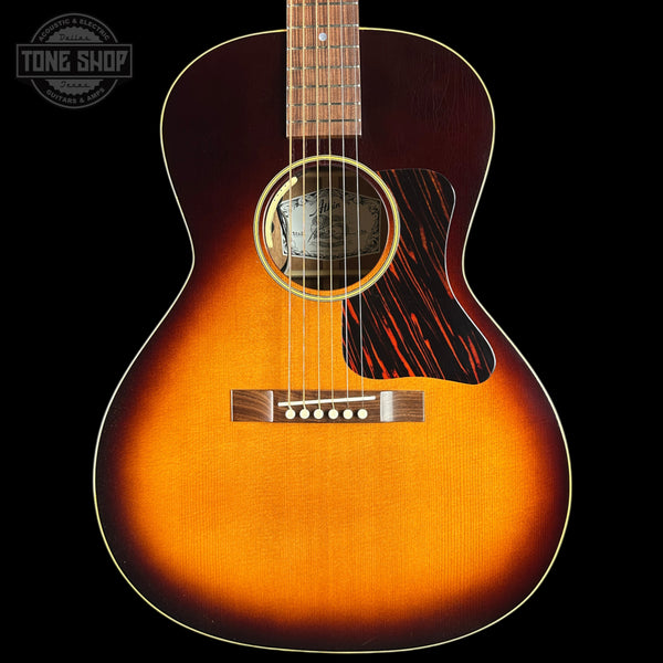 Acoustic guitar with a sunburst finish on a black background, featuring the Tone Shop logo.