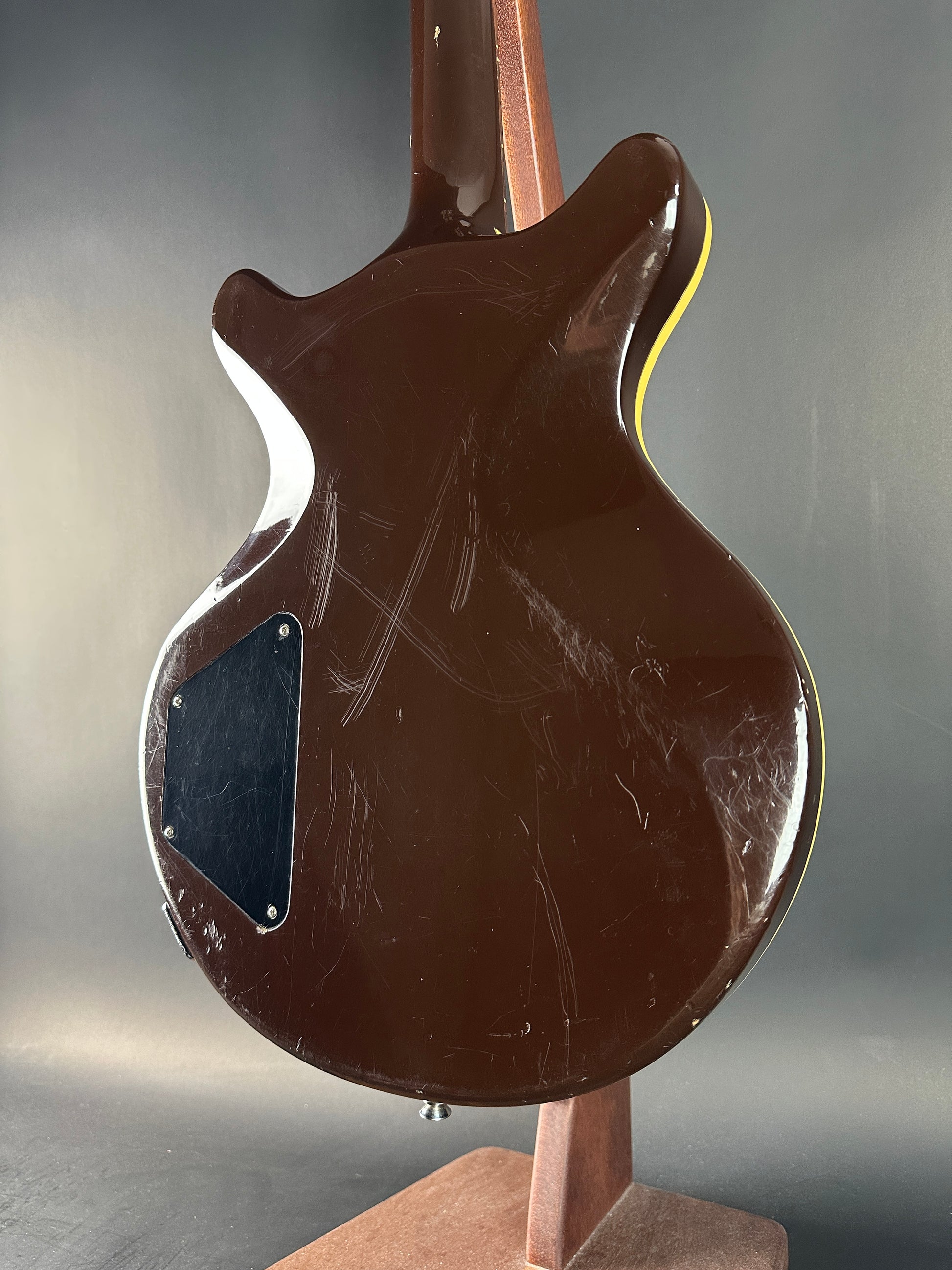 Close-up of a brown electric guitar with visible wear on a gray background