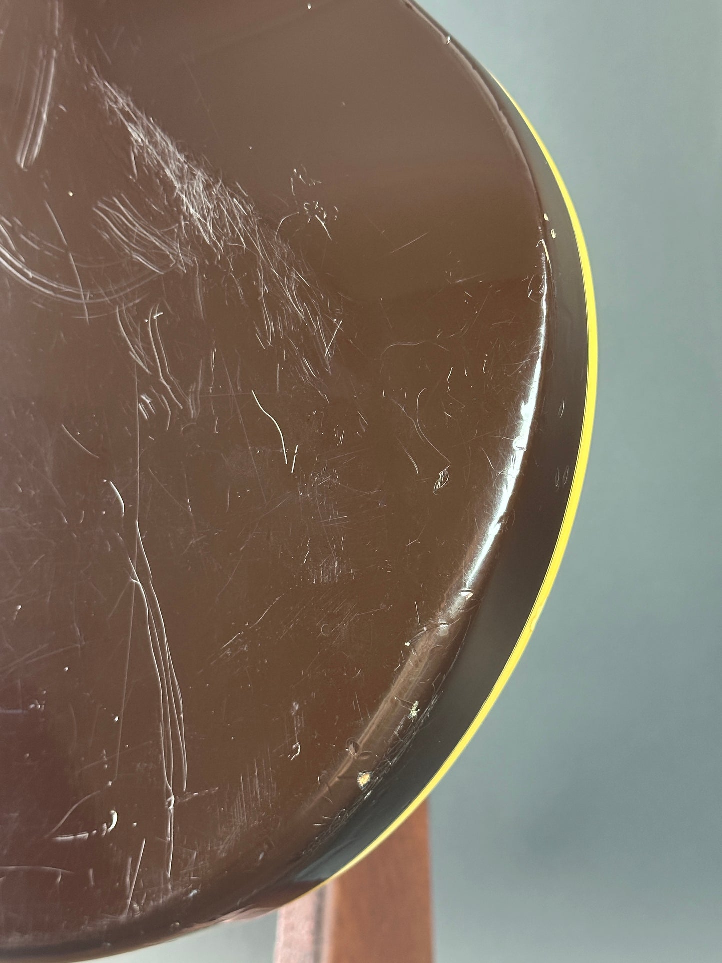 Scratched surface of a round object with a yellow rim on a gray background
