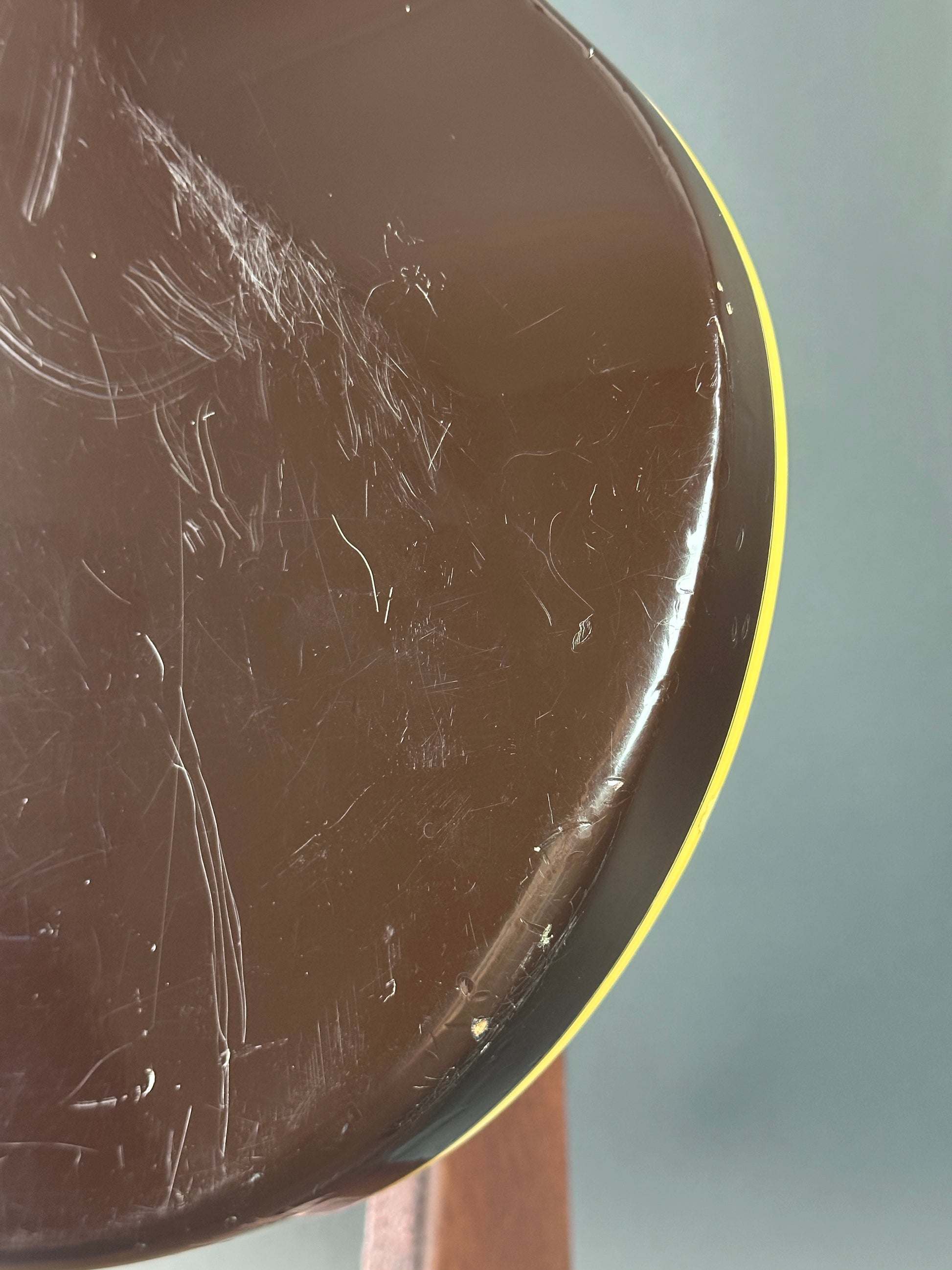 Scratched surface of a round object with a yellow rim on a gray background