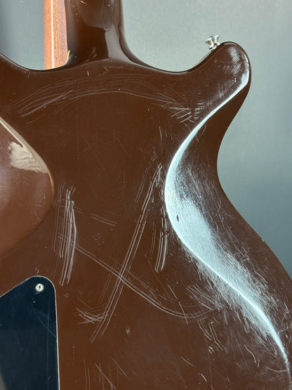 Close-up of a guitar's back with visible wear and tear on a gray background