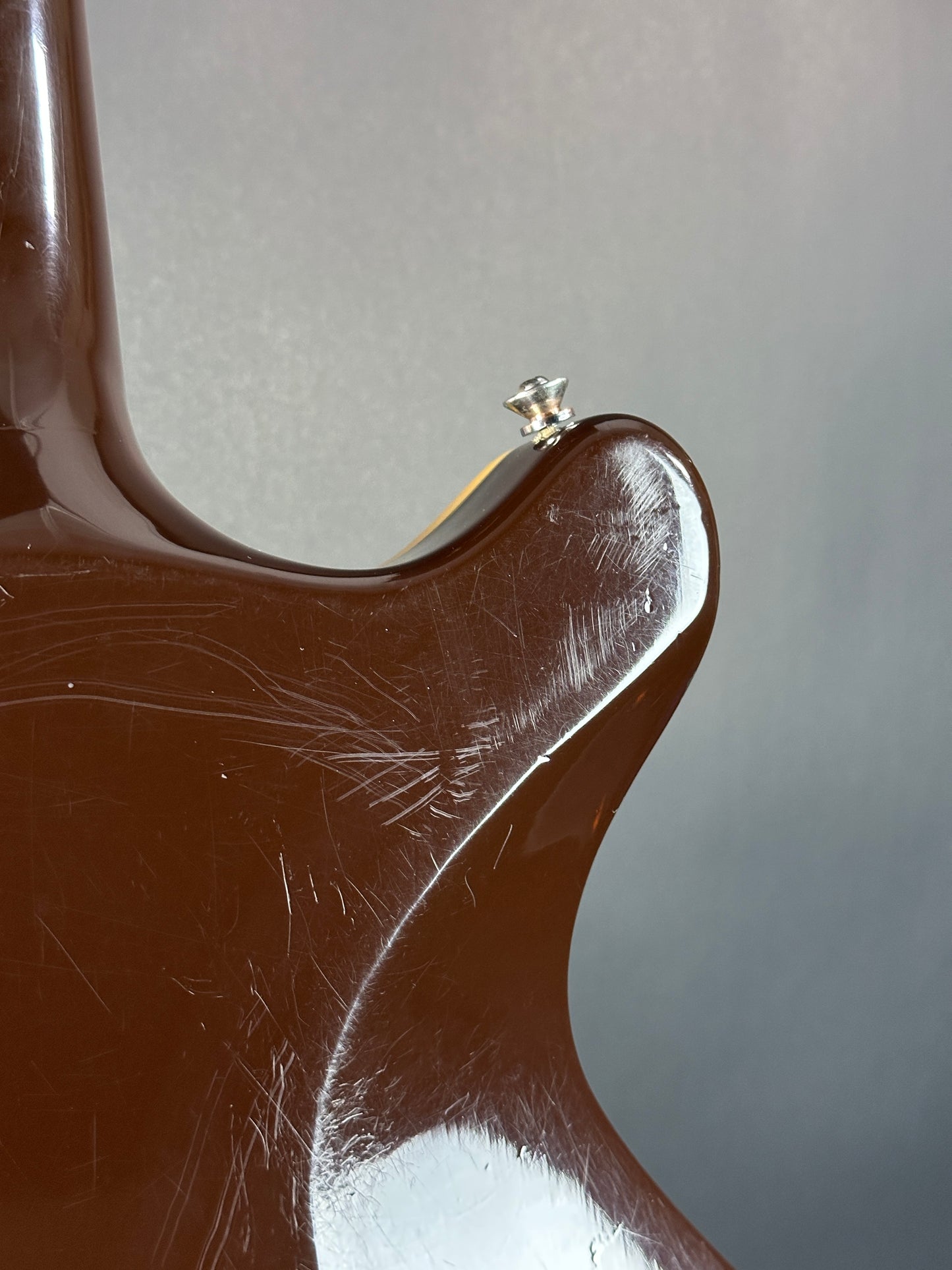Close-up of a brown leather chair with visible wear and tear on a gray background