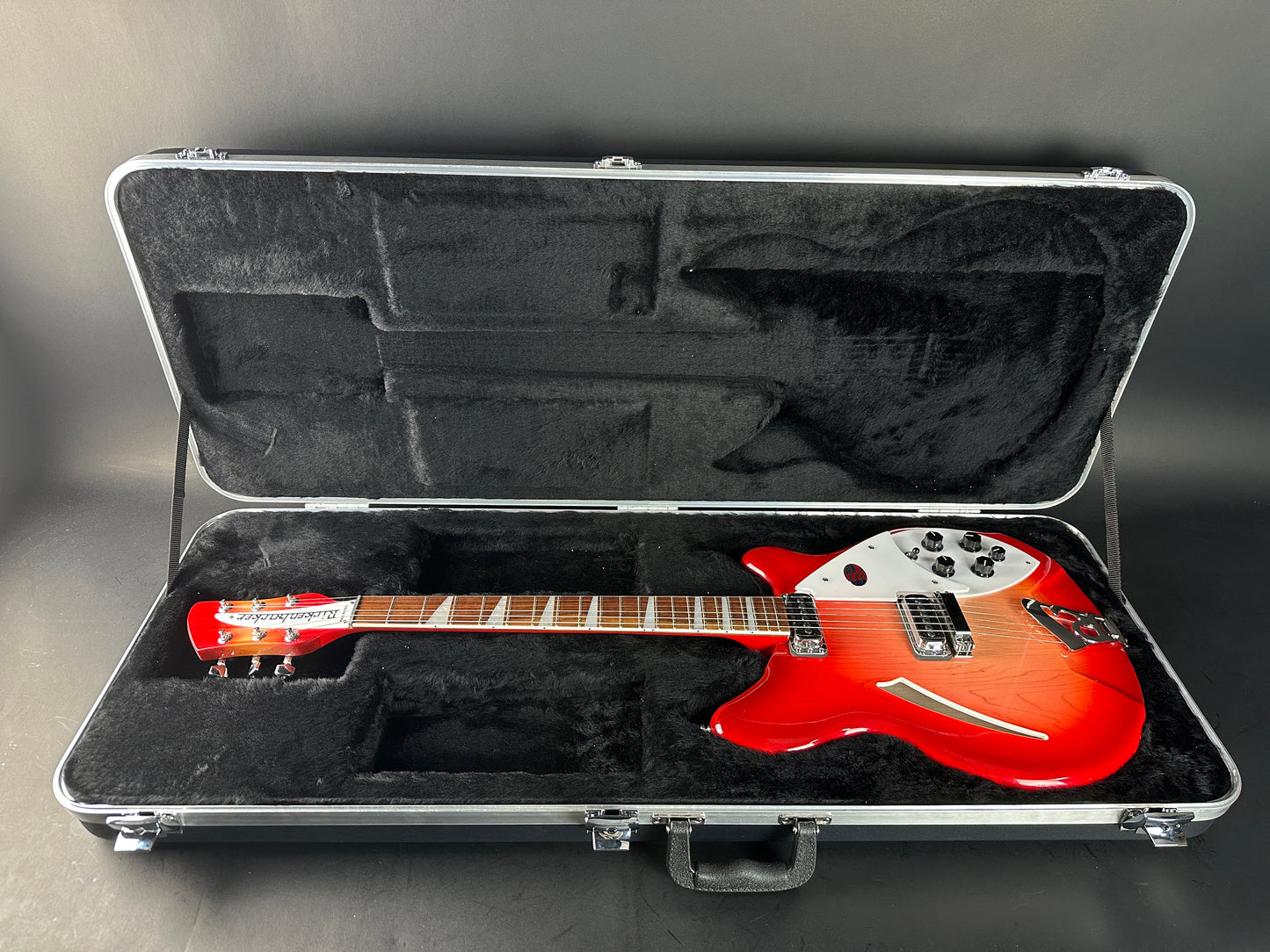 Red electric guitar in an open hard-shell case on a gray background