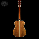 Back view of a wooden acoustic guitar on a black background with 'Tone Shop' logo.