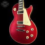 A red glitter electric guitar with a cream pickguard and gold-tone controls, shown against a solid black background. A Tone Shop watermark is visible in the top-left corner.