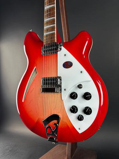 Close-up of a red electric guitar with a white pickguard on a dark background
