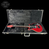 Red electric guitar in an open black case with 'Tone Shop' logo.