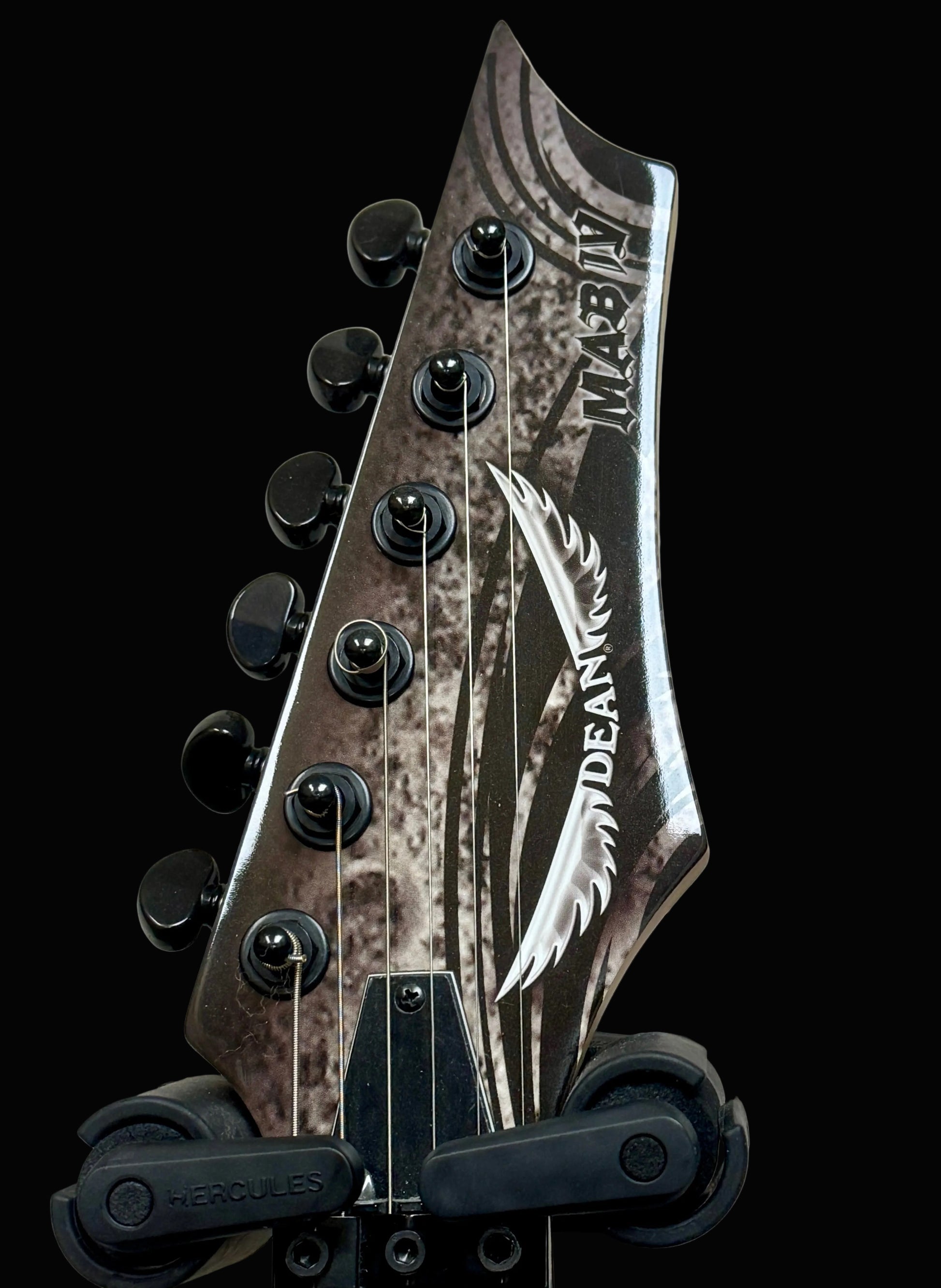 Guitar headstock with 'Dean' branding on a light gray background
