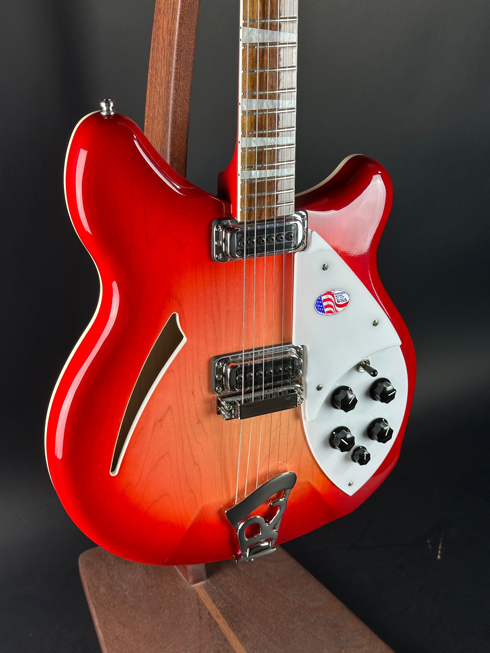 Red electric guitar with a white pickguard on a dark background