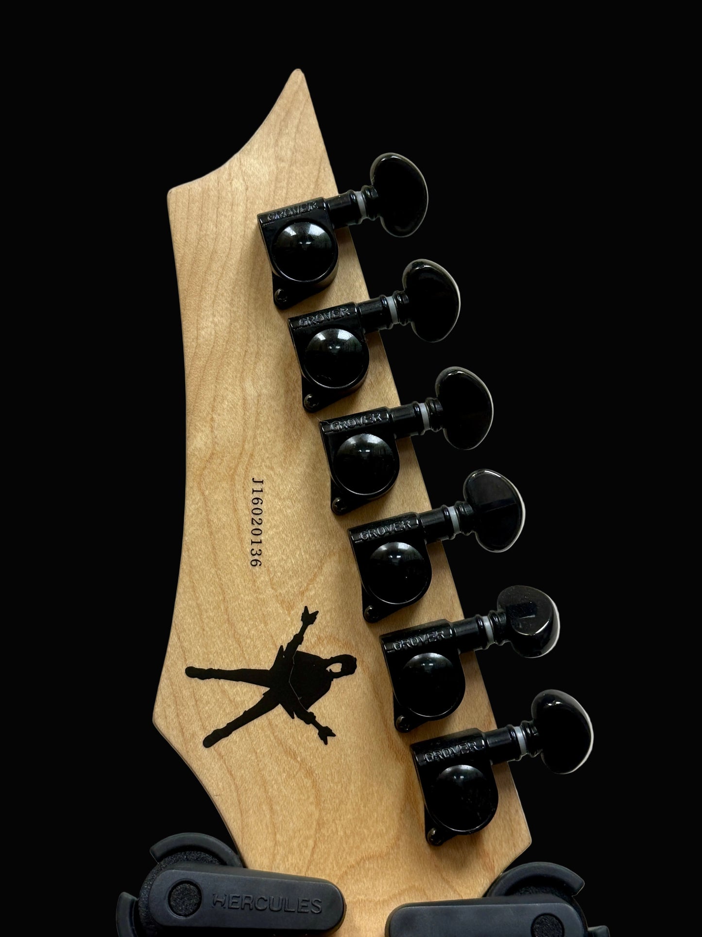 Guitar headstock with black tuning pegs on a light gray background