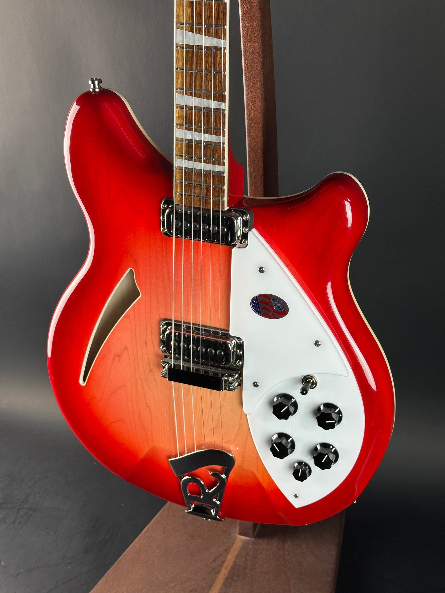 Red electric guitar with a white pickguard on a dark background