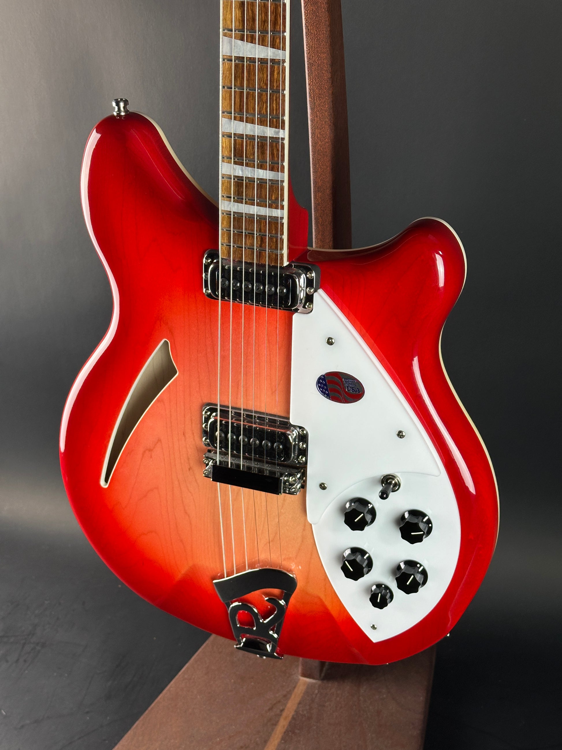 Red electric guitar with a white pickguard on a dark background