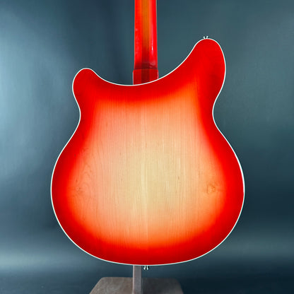 Red electric guitar body on a stand against a gray background