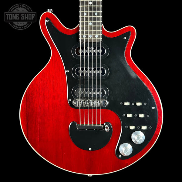 Red electric guitar with a black pickguard on a black background, featuring the Tone Shop logo.