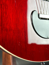 Close-up of a red electric guitar with a white pickguard.