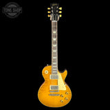 A classic electric guitar with a natural flamed maple top, black headstock, and gold tuners, shown against a solid black background with a Tone Shop watermark in the top-left corner.