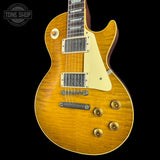A classic electric guitar with a natural sunburst finish, cream pickguard, and gold hardware, shown against a solid black background with a Tone Shop watermark in the top left corner.