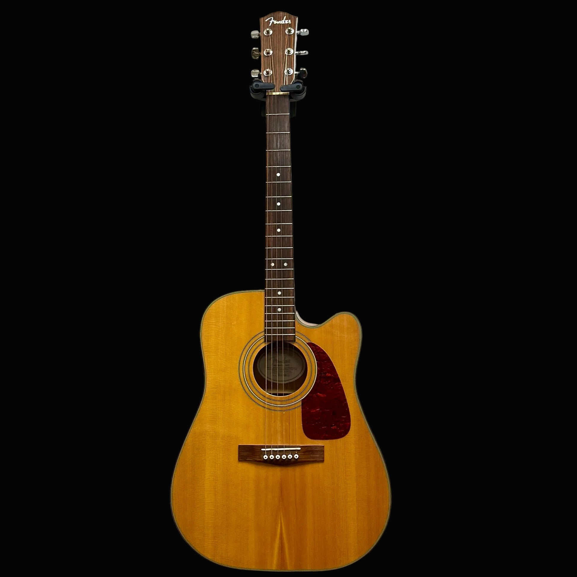 Acoustic guitar leaning against a textured white wall.