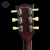 Close-up of the headstock of a dark reddish-brown acoustic guitar against a black background, showing six tuning pegs and the serial number CS 601560. A Tone Shop watermark is visible in the top left corner.