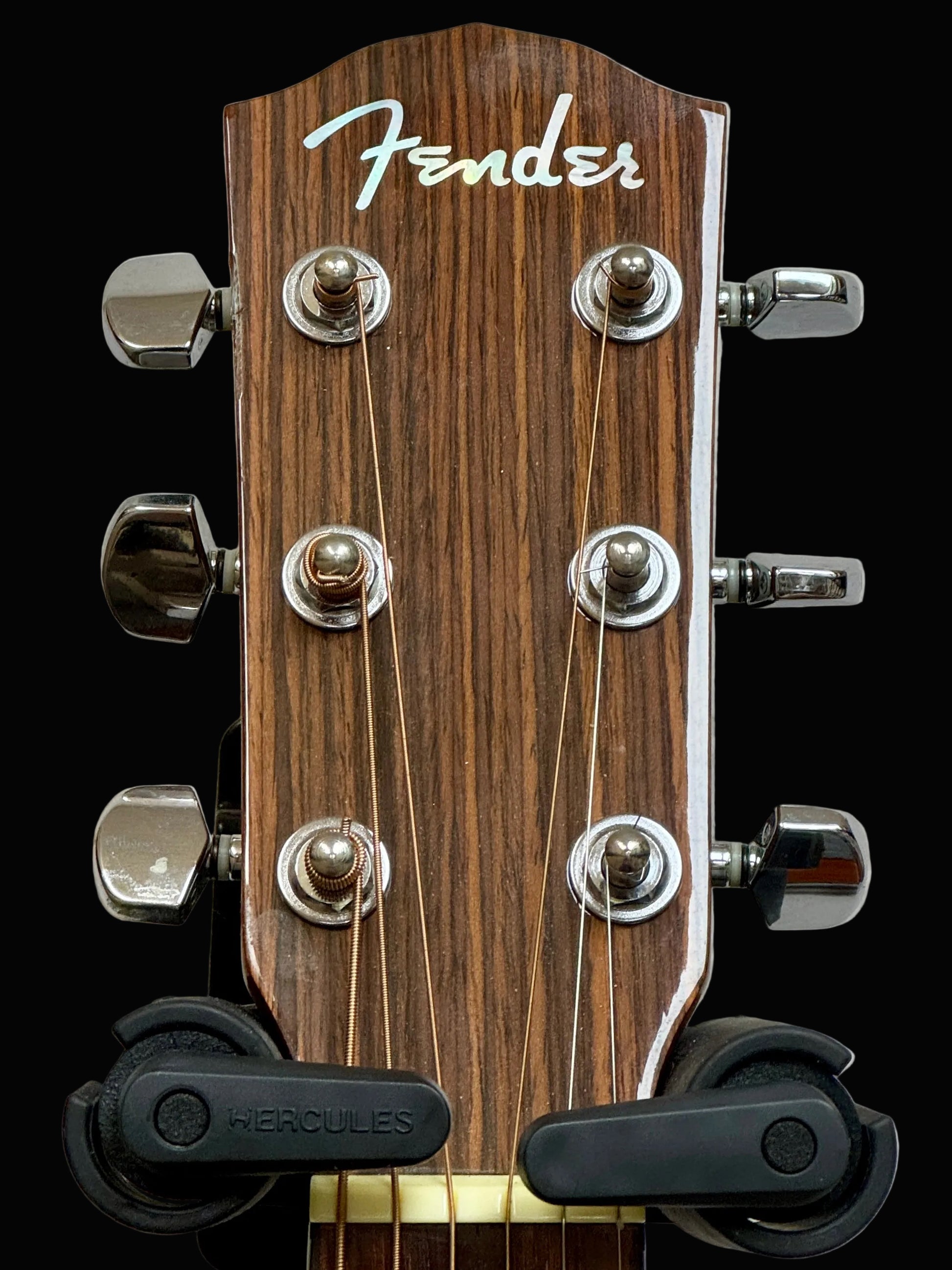 Fender guitar headstock with tuning pegs on a gray background