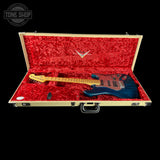 Guitar in a red-lined case with 'Tone Shop' logo.