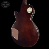 The back of a Gibson electric guitar with a glossy dark reddish-brown finish, featuring a cream-colored oval headstock badge and a matching cream pickguard, shown against a solid black background.