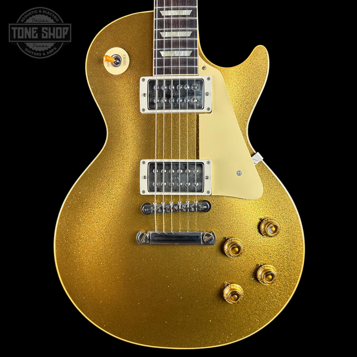 A gold glitter electric guitar body with a cream pickguard, chrome hardware, and a dark fretboard, shown against a black background with a Tone Shop watermark in the top left corner.