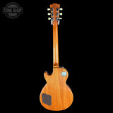 A Gibson electric guitar shown from the back, featuring a glossy natural wood finish and a black tailpiece, set against a solid black background with a Tone Shop watermark in the top left corner.