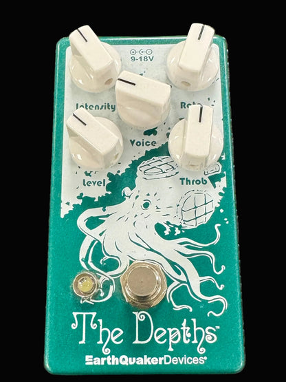 Guitar effects pedal with octopus design and 'The Depths' branding on a textured surface.