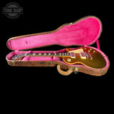 A gold electric guitar resting inside an open pink-lined hard case on a black background, with a Tone Shop watermark in the top-left corner.