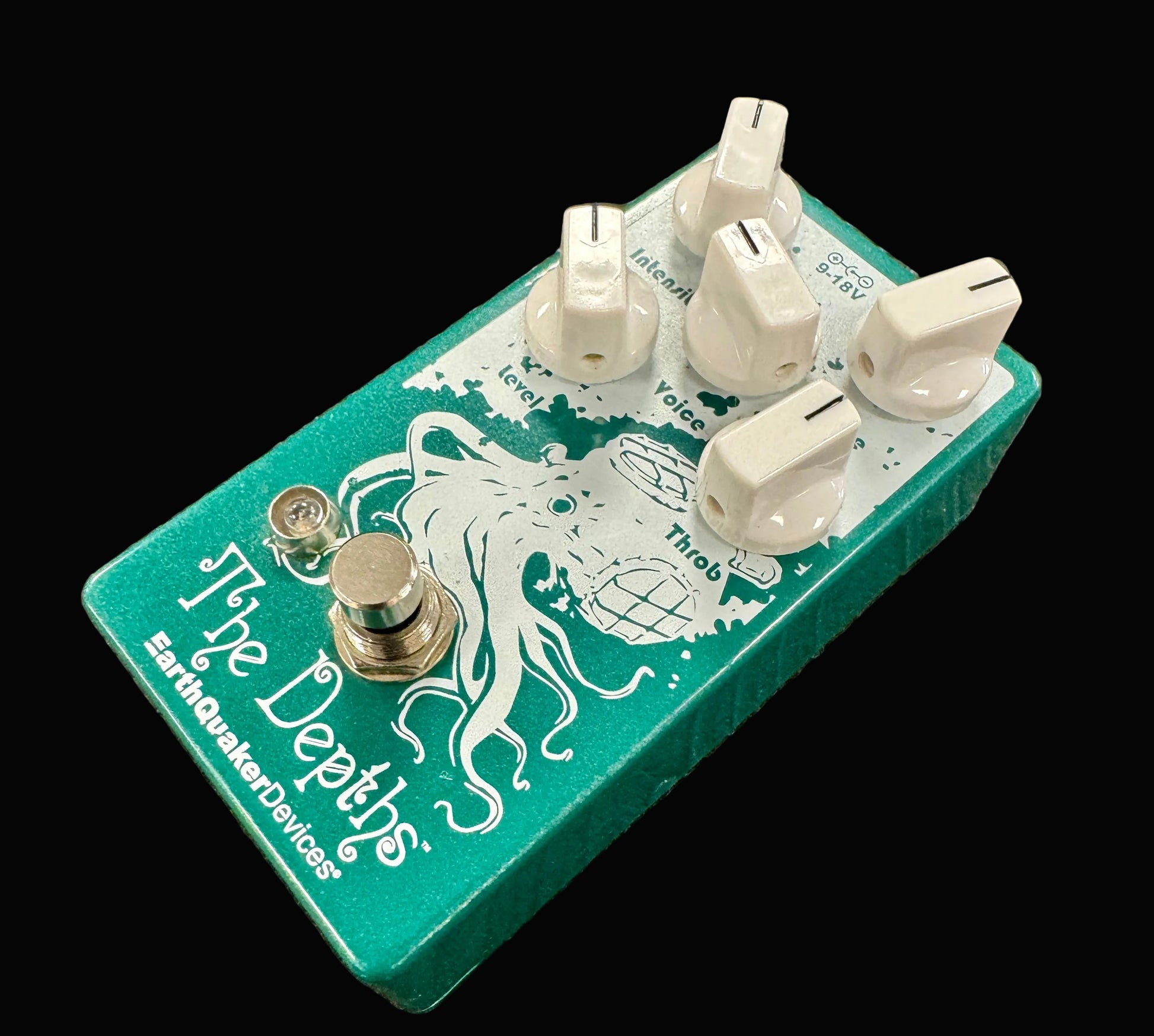 Green guitar effects pedal with white knobs and branding on a textured surface