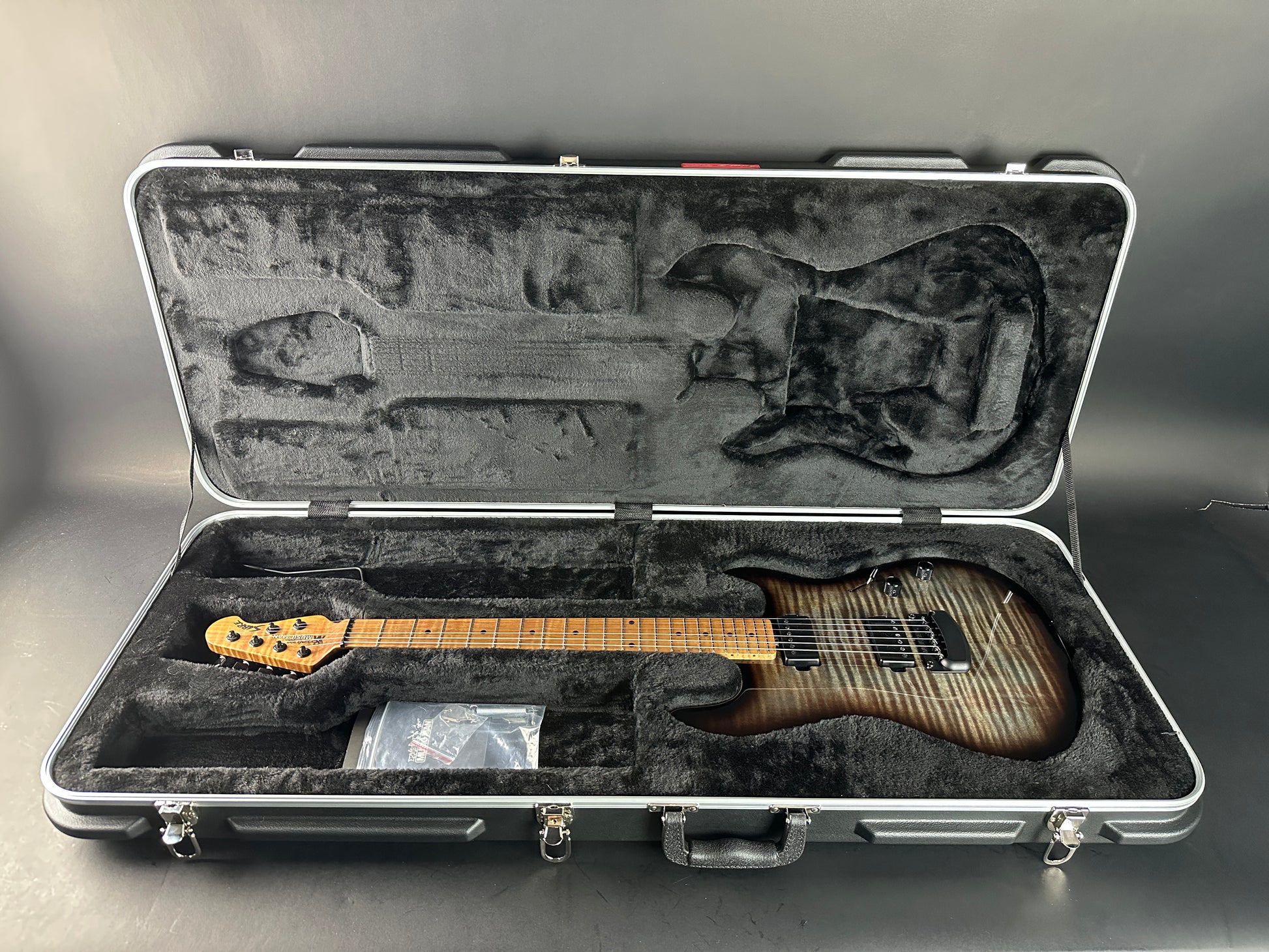 Guitar in a hard-shell case on a gray background