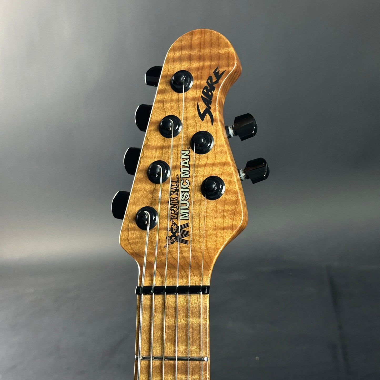Guitar headstock with 'Music Man' branding on a gray background