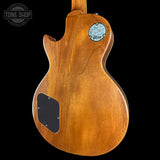 The back of a Gibson electric guitar with a natural brown wood finish, featuring a circular 'Floyd Rose' control plate and a black pickguard, shown against a solid black background.
