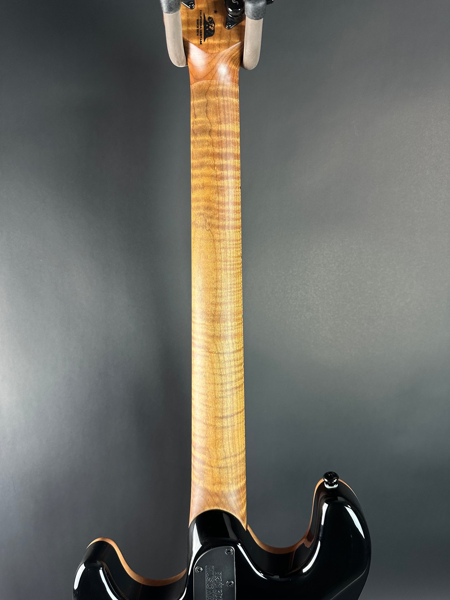 Close-up of a guitar neck and headstock on a gray background