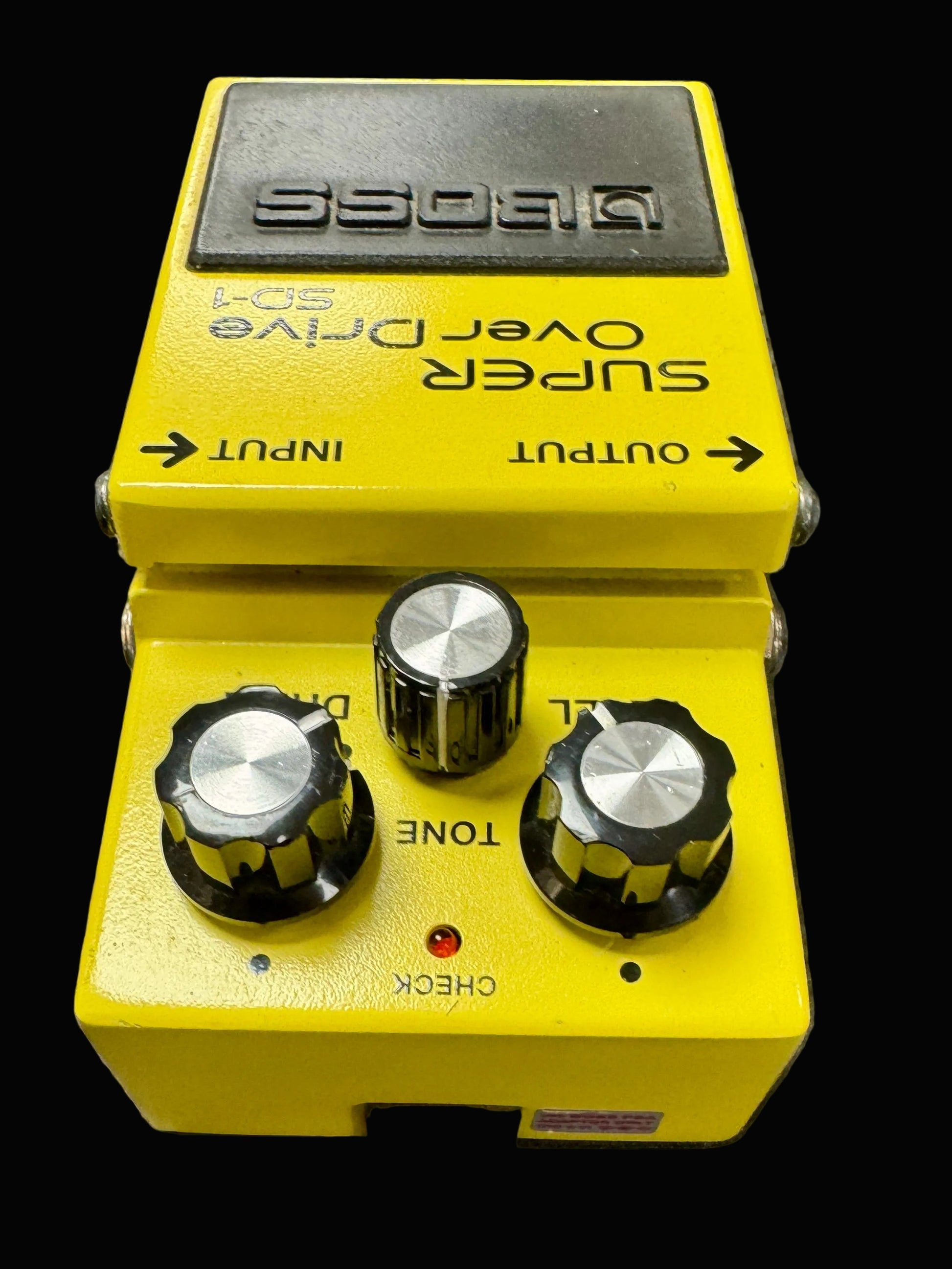 Yellow Boss guitar effects pedal on a textured surface