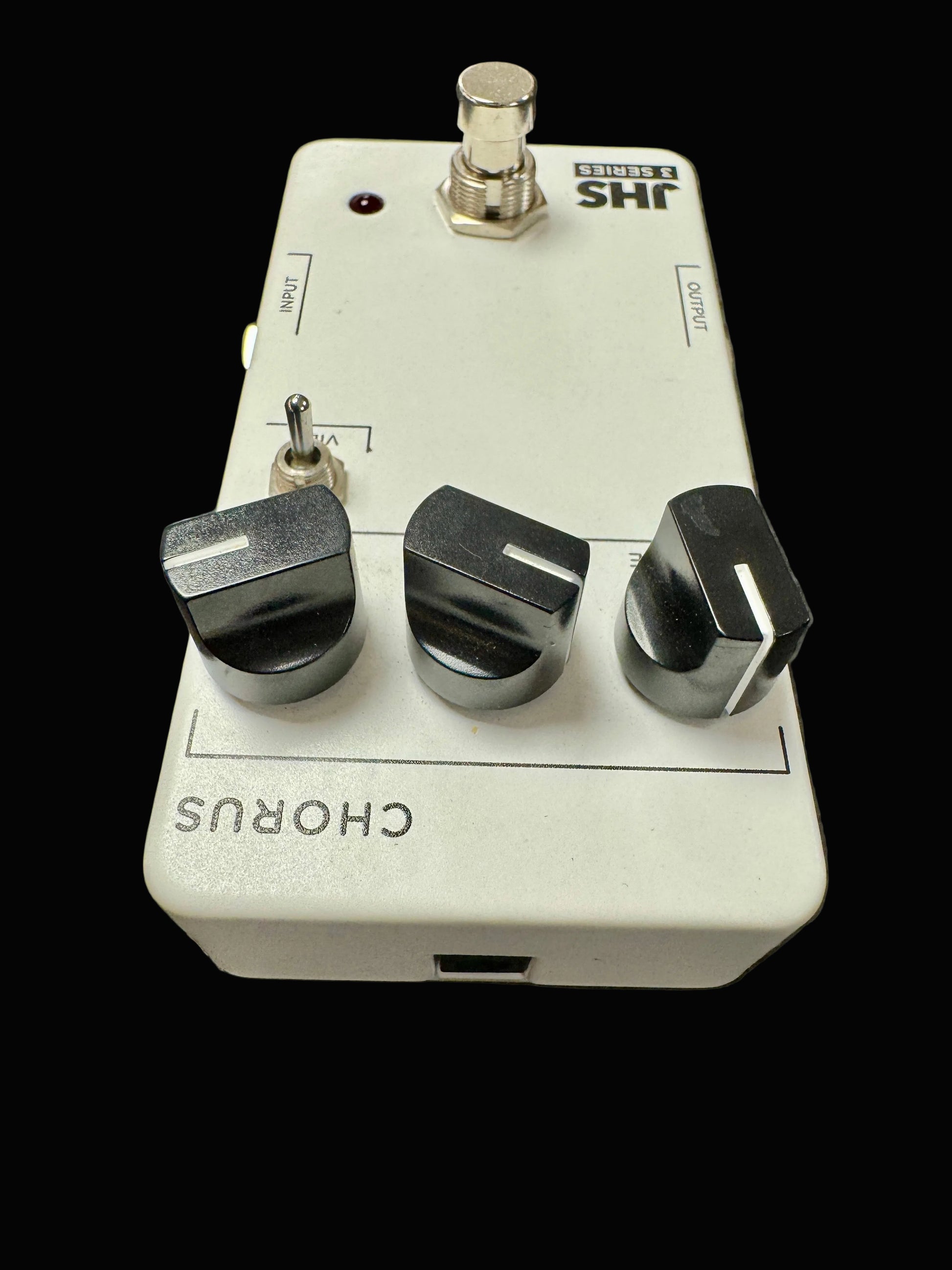 Guitar effects pedal with three knobs on a textured surface