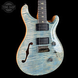 A custom electric guitar with a light blue and white flamed maple top, black hardware, and a natural wood body edge, shown against a black background with a Tone Shop watermark in the top left corner.