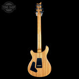A natural wood electric guitar shown from the back against a solid black background, with a Tone Shop watermark in the upper left corner.