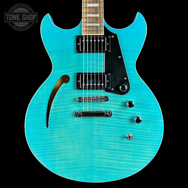 Turquoise electric guitar with a black pickguard on a black background, featuring 'Tone Shop' branding.