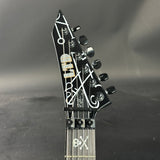 Close-up of a guitar headstock with intricate designs on a dark background
