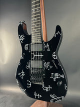 Black electric guitar with white designs on a gray background
