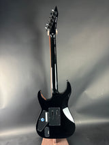 Black electric guitar on a reflective gray surface