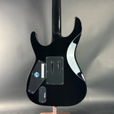 Black electric guitar on a stand against a gray background