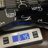 Digital scale displaying weight of a black electric guitar on a wooden surface.