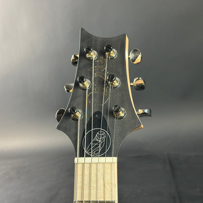 Close-up of a guitar headstock with tuning pegs on a dark background