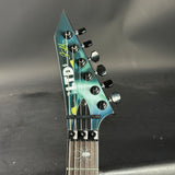 Close-up of a guitar headstock with branding on a dark background
