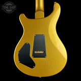 The back of a gold metallic electric guitar body with black pickguards and a black pickup cover, shown against a solid black background. A Tone Shop watermark is visible in the top-left corner.