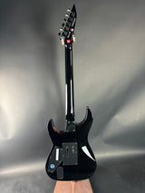 Black electric guitar on a reflective surface with a neutral background