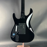 Black electric guitar on a stand against a gray background